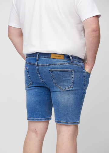 Denim middle-slim shorts set bagfra tæt på en plus-size model for at vise detaljer.