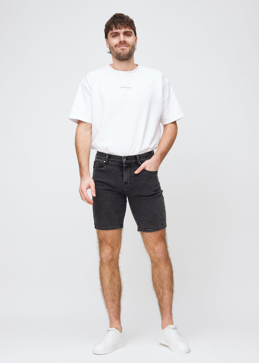 Fuldt billede af model i mørkegrå denim middle-slim shorts.