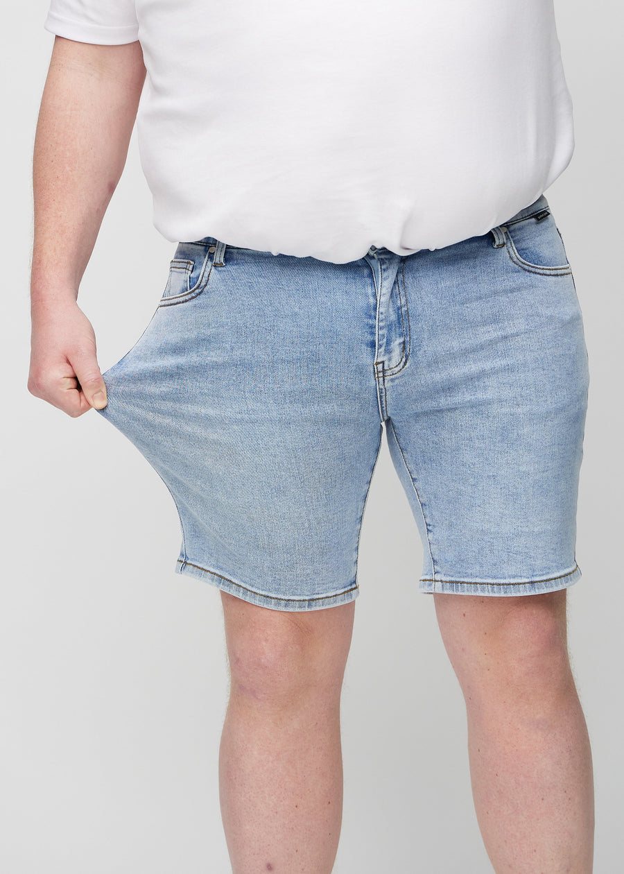 Plus-size model strækker shortsene ved låret for at vise stretch.
