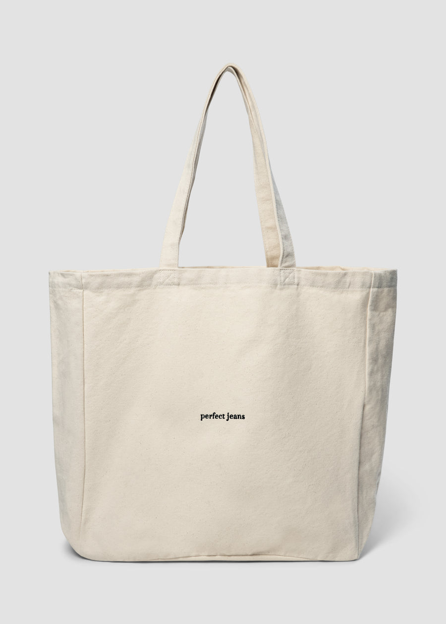 Beige tygkasse från Perfect Jeans med svart logotyp framtill.