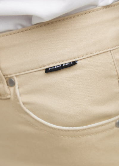 Forlommen på et par beige jeans, hvor man kan se logoet på en plus-size model.