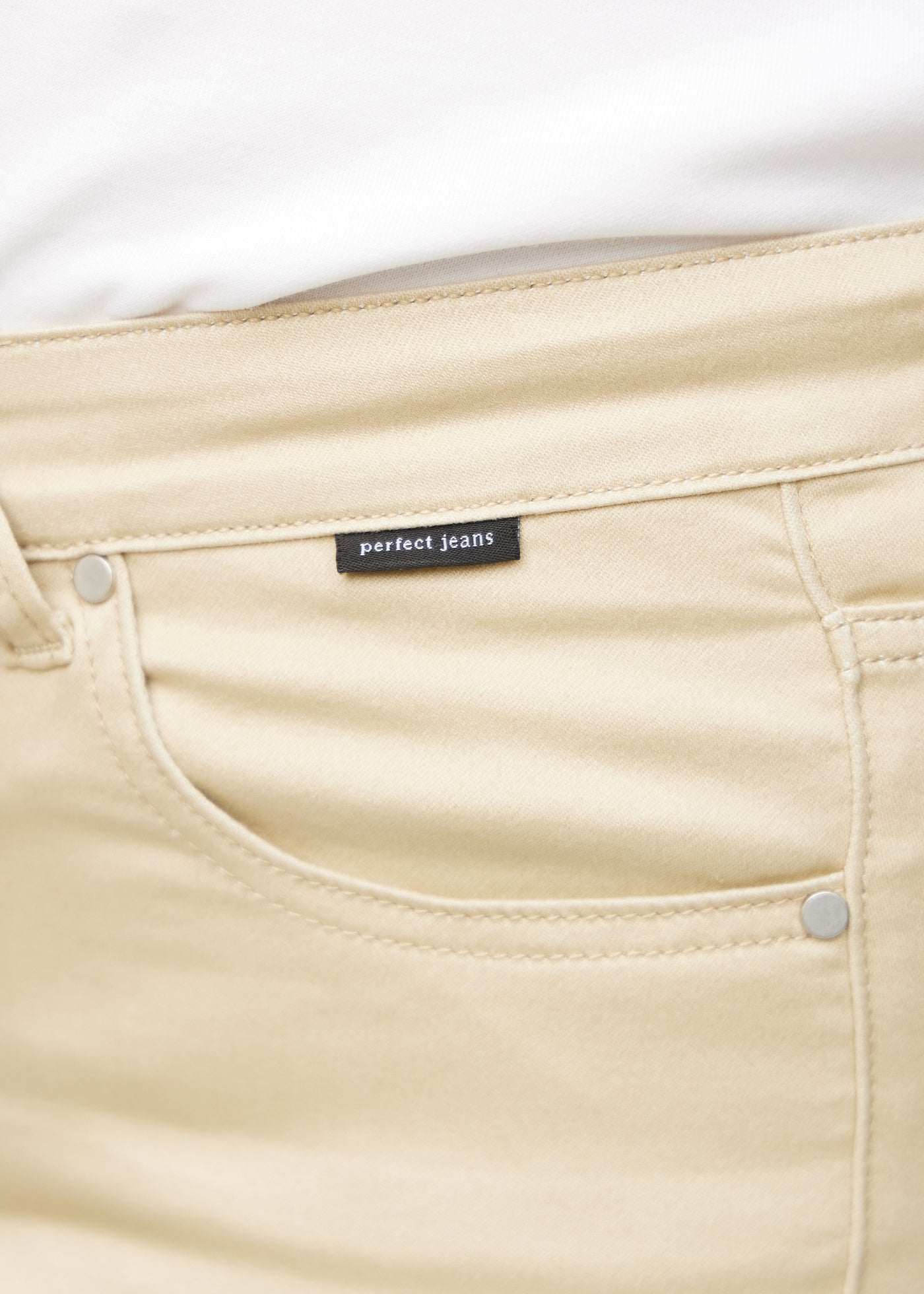Forlommen på et par beige jeans, hvor man kan se logoet.