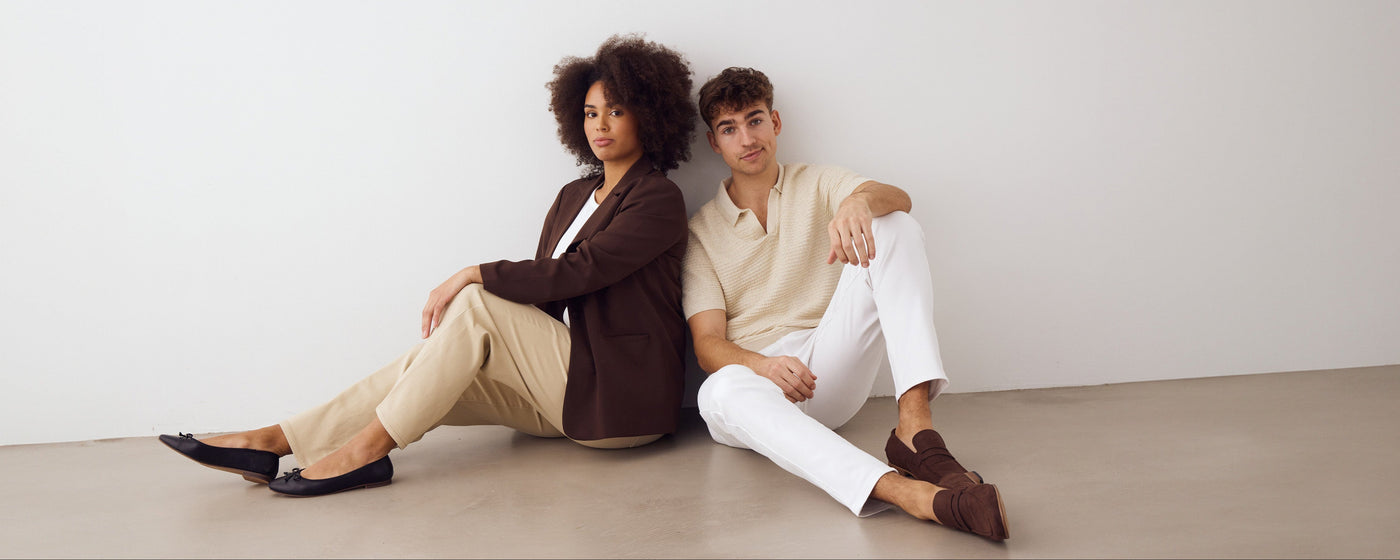 Kvinde iført beige jeans og mand iført hvide jeans, der sidder på gulvet