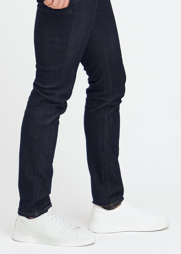 Djupmörkblå denimjeans för män i färgen Midnights med slim passform, visade på nära håll vid anklarna för att framhäva den smala benöppningen.
