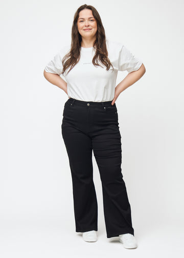 Plus-size model går ind i billedet, strækker i jeansene, viser dem frem ved at dreje rundt, og forlader derefter billedet.