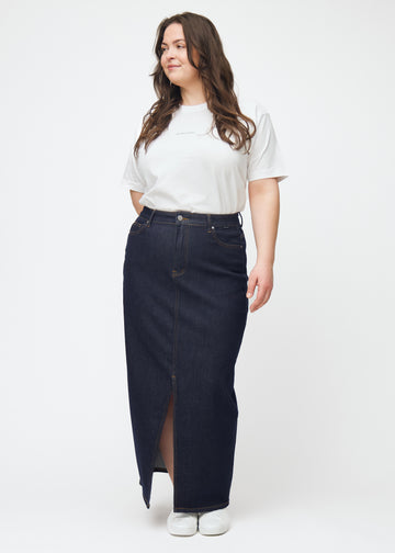 Plus-size model viser lang dyb mørkeblå denim nederdel til kvinder i farven Midnights i bevægelse og demonstrerer slids og materiale.