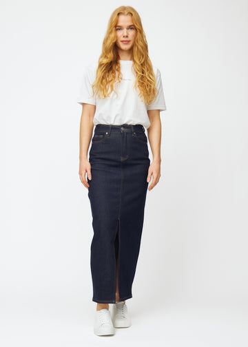 Model viser lang dyb mørkeblå denim nederdel til kvinder i farven Midnights i bevægelse og demonstrerer slids og materiale.