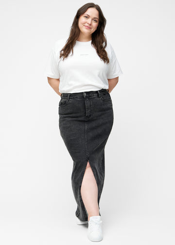 Plus-size model viser lang, mørkegrå denimnederdel i farven Shadows med regulær pasform i bevægelse og demonstrerer slids og materiale.